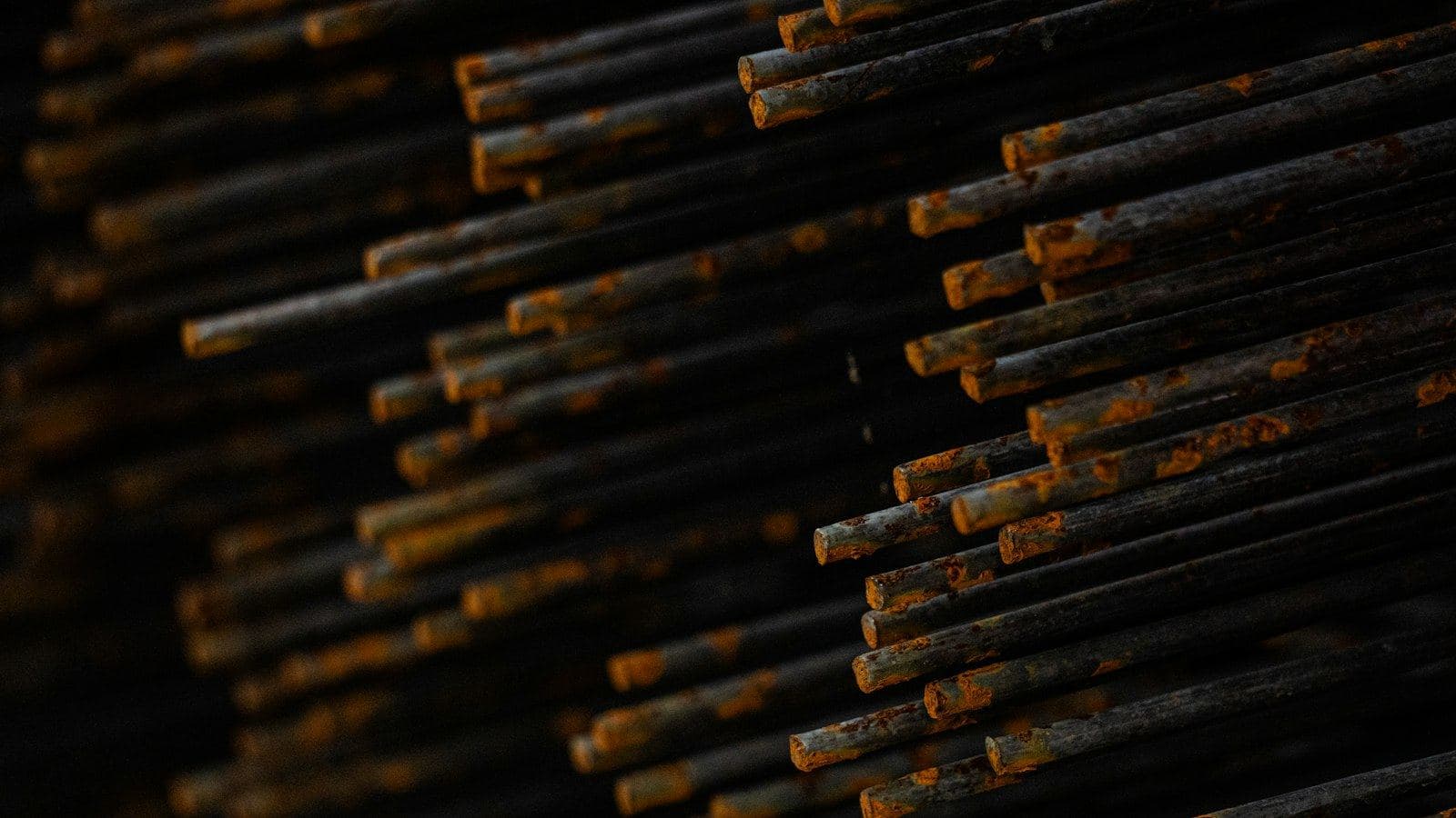 Pontas de vergalhões de aço empilhados, cobertas de ferrugem alaranjada