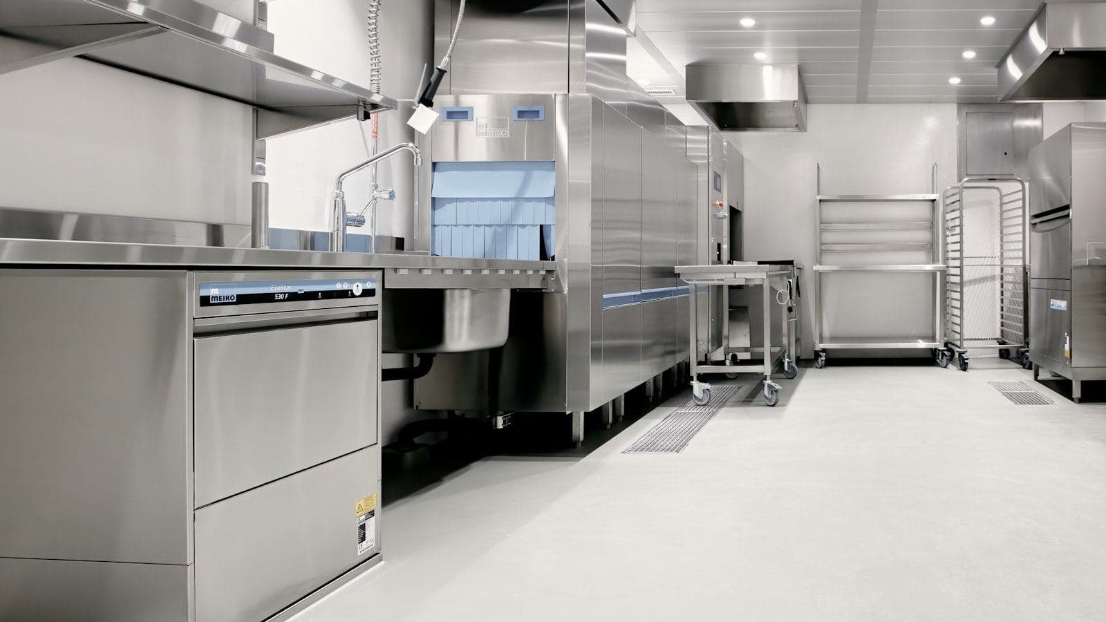 Cozinha industrial com bancadas, coifa e equipamentos de aço inox