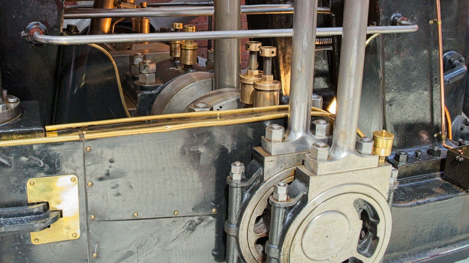 Máquina antiga com copos de lubrificação e tubos dourados de liga de cobre junto aos mancais