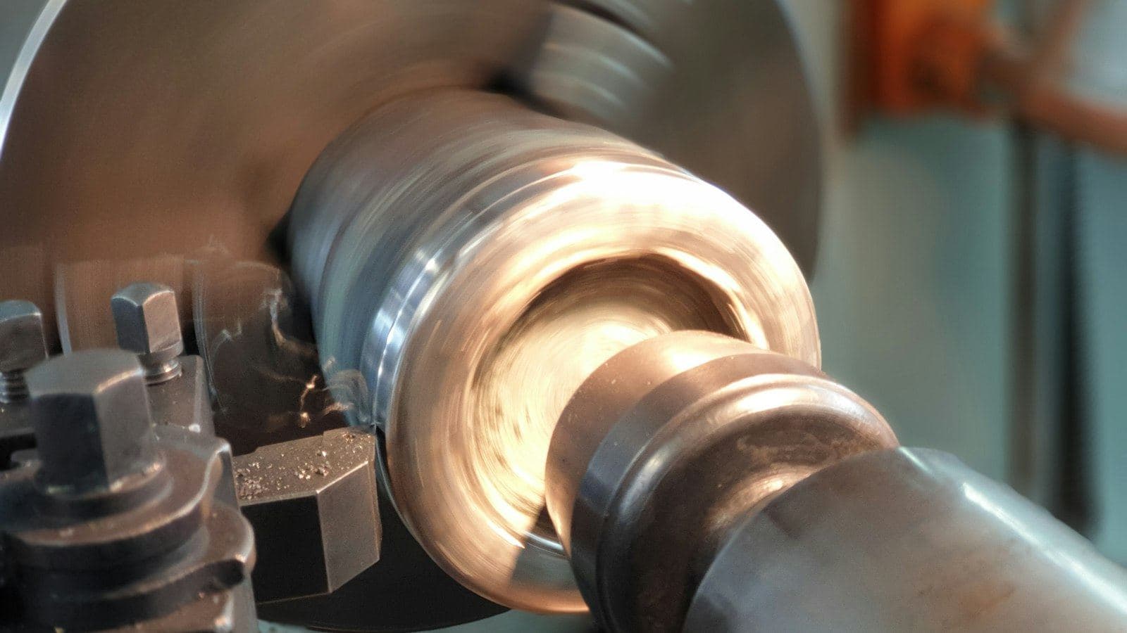 Barra de metal girando no torno enquanto a ferramenta retira material da superfície